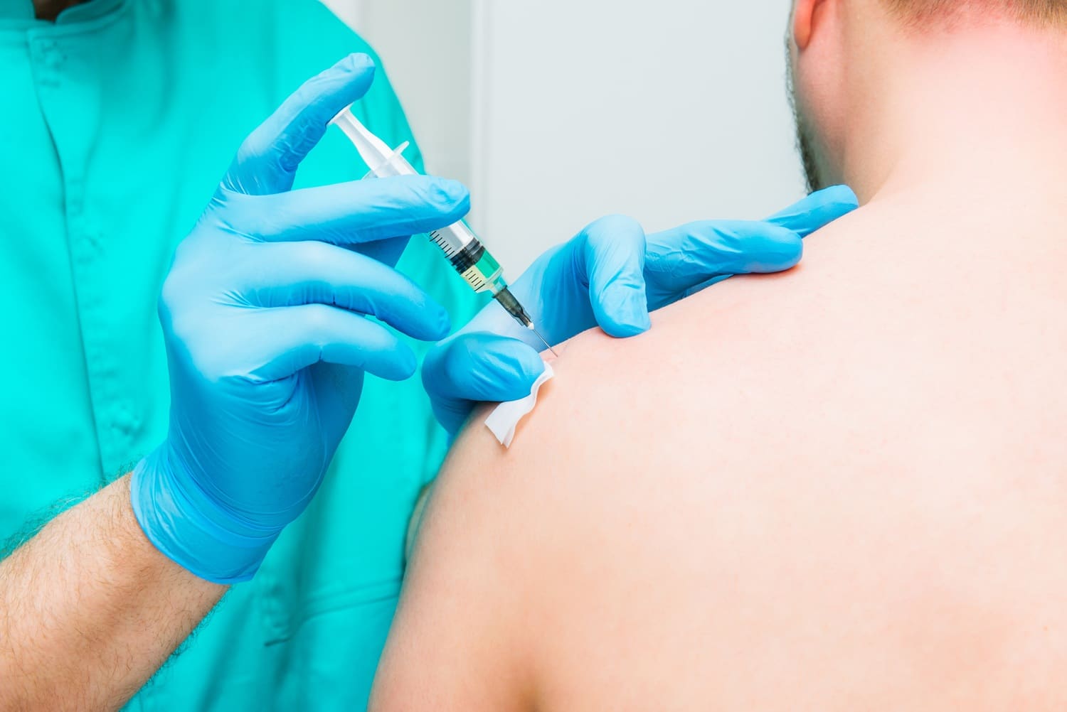 Doctor makes an injection therapy, into deltoid muscle of male patient.